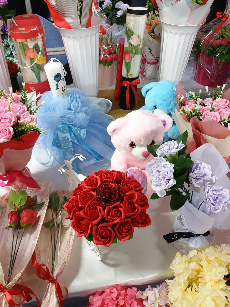 Buchet de trandafiri roșii din săpun, ursuleți de pluș și lumânări decorate, pe masa din magazin